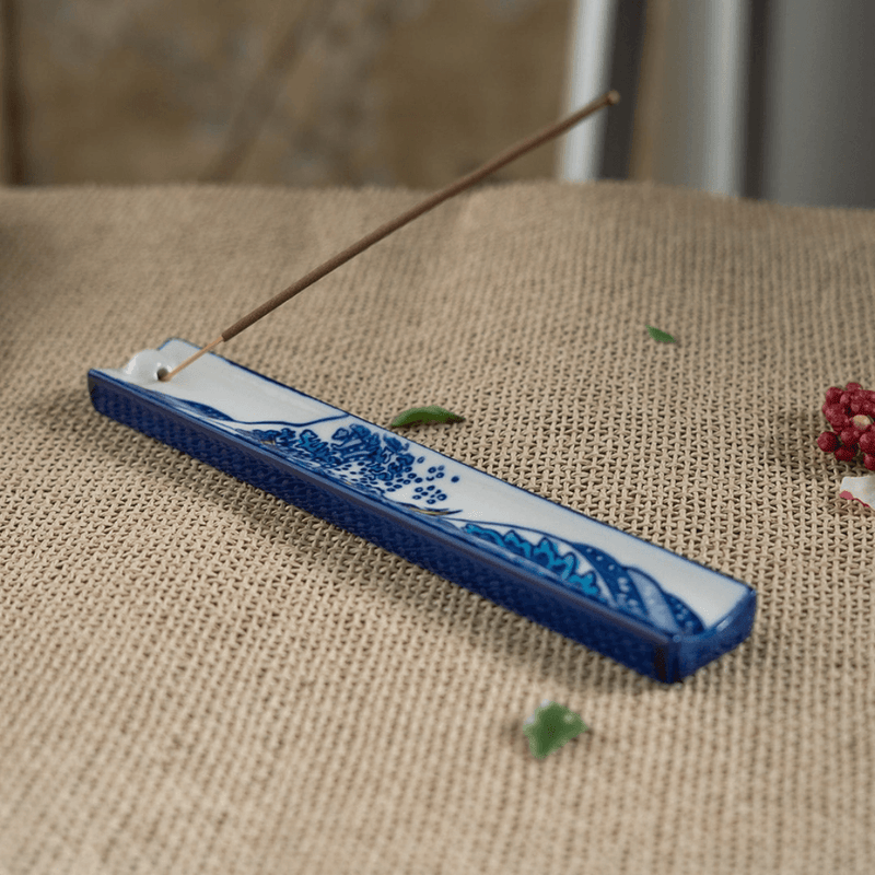 Handpainted ceramic Great Wave incense holder with stick incense on a woven surface
