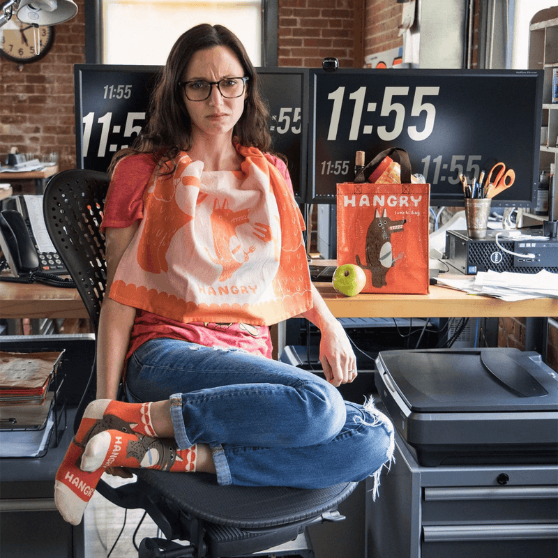 Person holding Hangry dish towel in office, orange woven design, lifestyle photo.