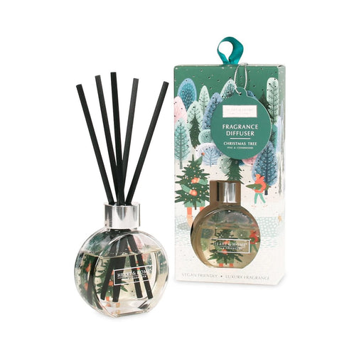 Heart & Home Christmas Tree reed diffuser in clear round glass with black reeds beside the illustrated green gift box with ribbon hanger.