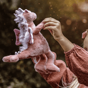 Hearts pink dragon plush from Bearhouse by Charlie Bears 2025 held up outdoors, showing fluffy mane, wings and spine detail