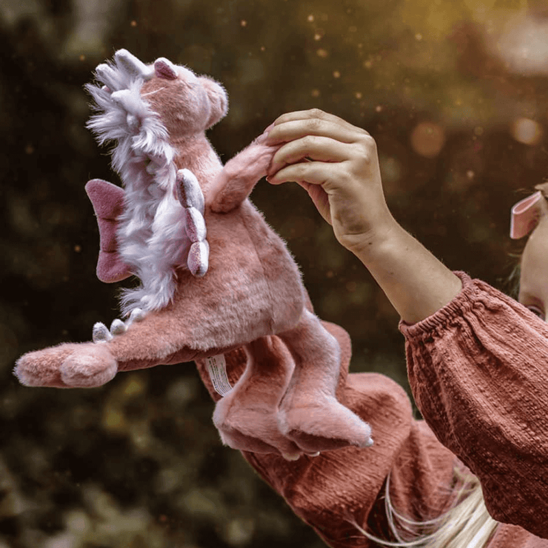 Hearts pink dragon plush from Bearhouse by Charlie Bears 2025 held up outdoors, showing fluffy mane, wings and spine detail