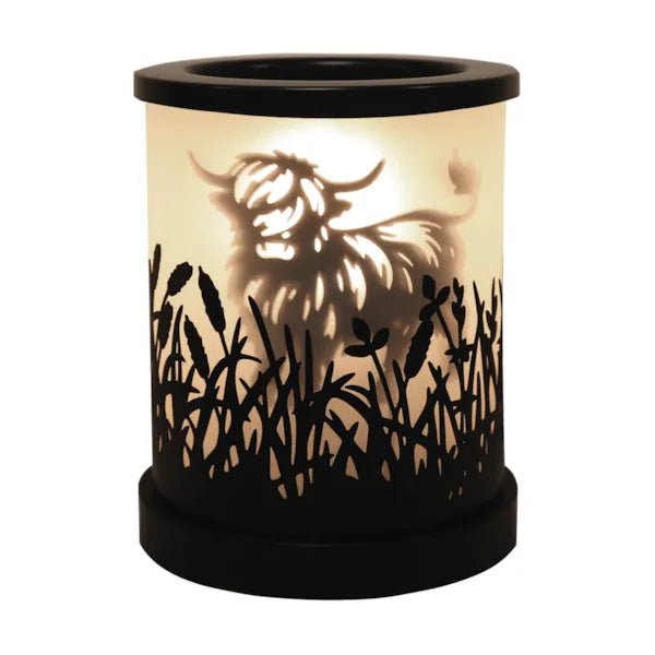 Highland cow silhouette electric wax melt burner glowing warmly with black meadow cut-out detailing.