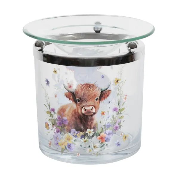 Clear glass tealight wax melt burner with a Highland cow and wildflower illustration and a glass dish on top.