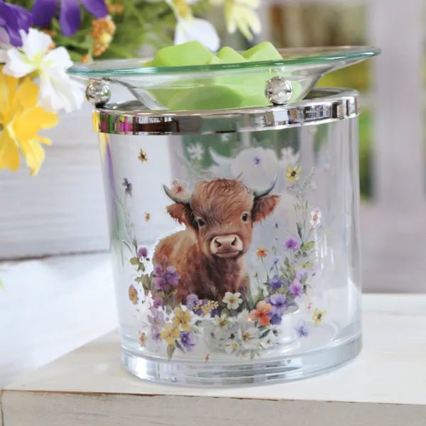 Highland cow tealight wax melt burner styled on a shelf with green wax melts in the top dish.
