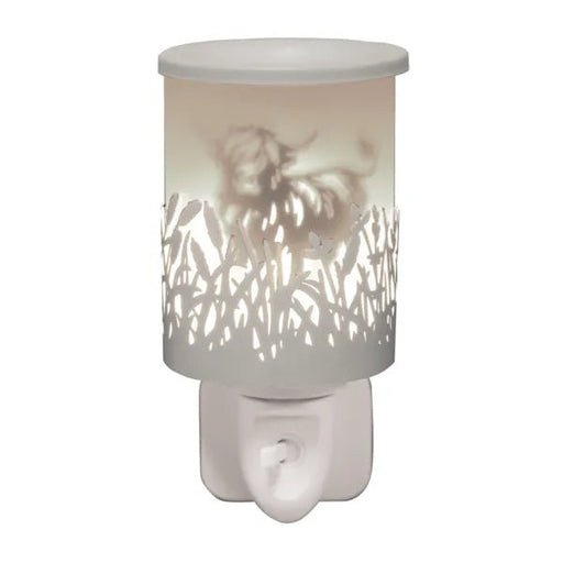 White plug in wax melt burner glowing with a Highland cow silhouette and cut-out grass detail, with an on/off switch on the plug base.