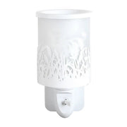 White plug in wax melt burner unlit, showing the cut-out grass design and frosted panel with the Highland cow silhouette behind.