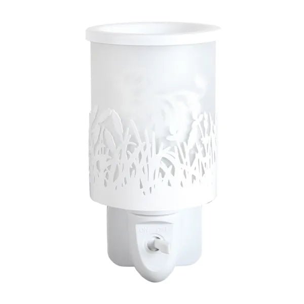 White plug in wax melt burner unlit, showing the cut-out grass design and frosted panel with the Highland cow silhouette behind.