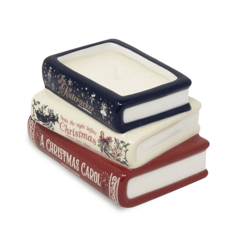 Angled view of Holiday Classics stacked books candle showing the ceramic book-shaped vessel, white page details and wax-filled top