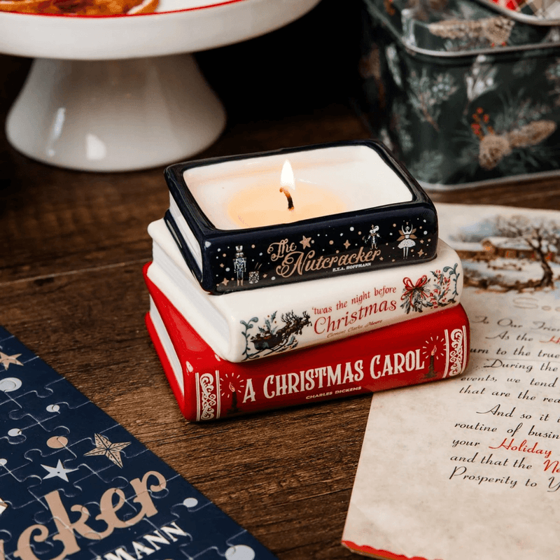 Lit Holiday Classics stacked books candle on a wooden table surrounded by festive decorations and Christmas stationery