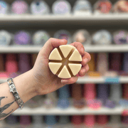 Honey Meadow wax melt segments held in hand with colourful wax melt display in the background