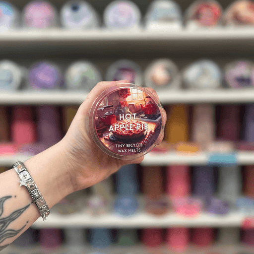 Hot Apple Pie wax melt pot held in hand with colourful wax melt display in the background
