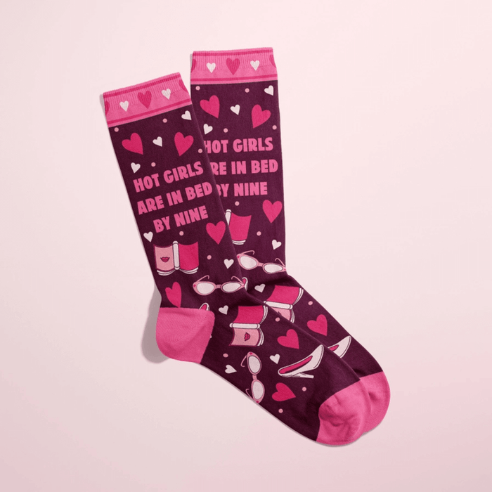 Overlapped burgundy women’s crew socks with pink heels, hearts and bedtime icons, slogan Hot girls are in bed by nine.
