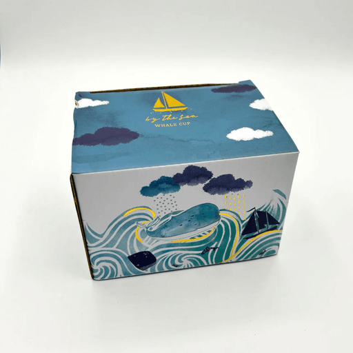 Illustrated gift box for the By The Sea Whale Cup featuring waves, clouds and sailboat artwork