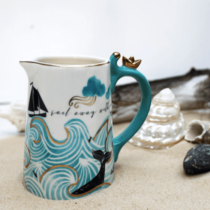Lifestyle photo of the jug on sand with shells, showing the nautical wave design