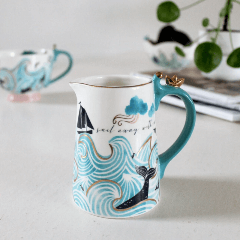 Jug on a table setting showing the gold origami boat on the handle and nautical design