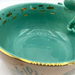 Close-up inside the bowl showing glossy teal glaze and gold-foil fish pattern