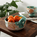 Lifestyle photo of the Coral Octopus Bowl holding fruit on a wooden table
