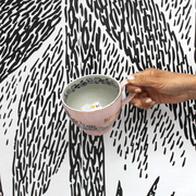 House of Disaster Moomin Love cup held in hand showing the grey interior and hidden Moomin figure inside
