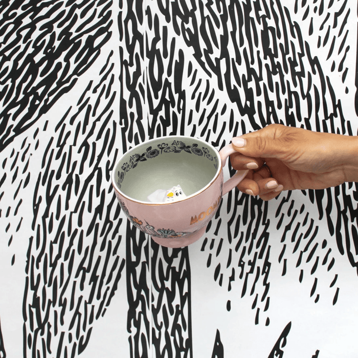 House of Disaster Moomin Love cup held in hand showing the grey interior and hidden Moomin figure inside