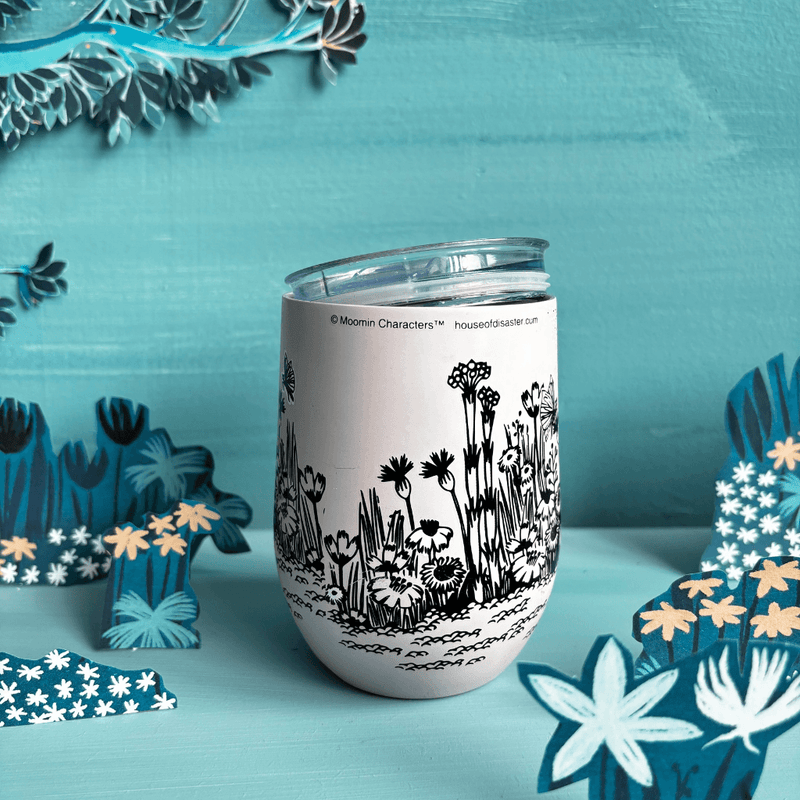 Reverse lifestyle view of House of Disaster Moomin Love keep cup with floral meadow artwork and lid resting on top