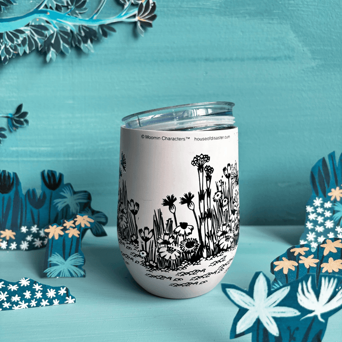 Reverse lifestyle view of House of Disaster Moomin Love keep cup with floral meadow artwork and lid resting on top