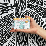 House of Disaster Moomin floral card holder held in hand showing Moomin and Snorkmaiden on the front