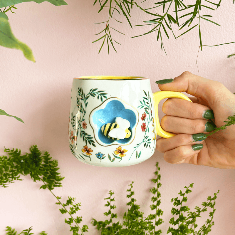 Cup held in hand showing scale, yellow handle and the 3D bee nook detail