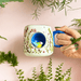 Cup held in hand showing scale, blue handle and the 3D bird nook detail
