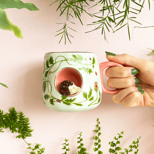 Cup held in hand showing scale, pink handle and the 3D hedgehog nook detail