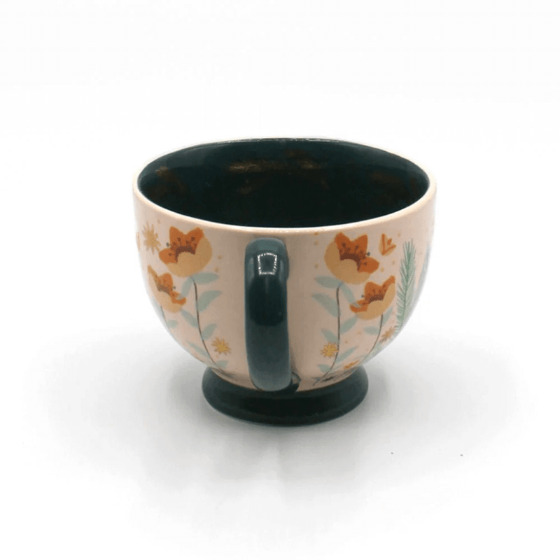 Rear view showing the teal handle, soft pink exterior and floral pattern around the cup