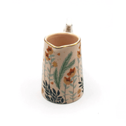 Angled view showing the pouring spout, pink interior and foliage design around the jug