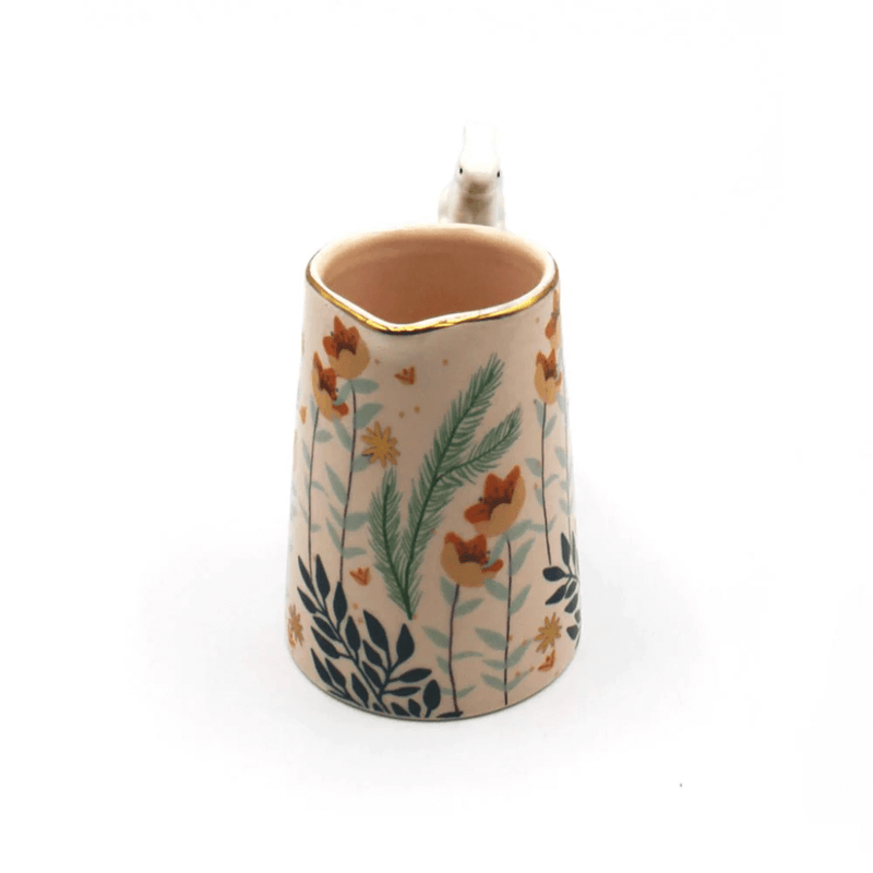 Angled view showing the pouring spout, pink interior and foliage design around the jug