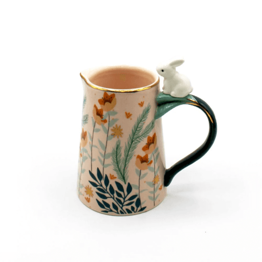 Front view of the pink porcelain jug with foliage print and rabbit perched on the handle