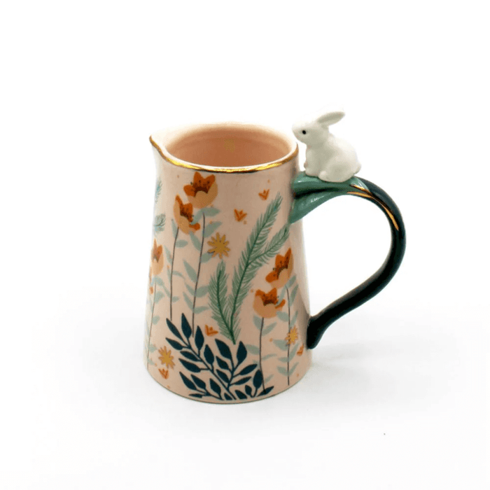 Front view of the pink porcelain jug with foliage print and rabbit perched on the handle