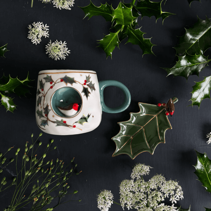 Flatlay of the Robin Cup with festive greenery, featuring the 3D robin nook on the front