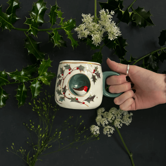 Robin Cup held in hand, showing the 3D robin nook, holly design and green handle