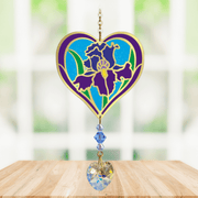 Heart-shaped Iris Crystal Suncatcher with purple iris motif and faceted rainbow-making heart prism hanging in a sunny window

