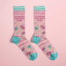 Pair of pink women’s novelty crew socks with teal accents, donuts, macarons and ice-cream print, and “It’s illegal to be mean to me” text.