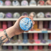 Jasmine Skies wax melt pot held in hand with colourful wax melt display in the background