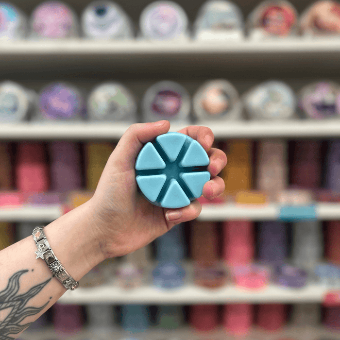 Jasmine Skies wax melt segments held in hand with colourful wax melt display in the background