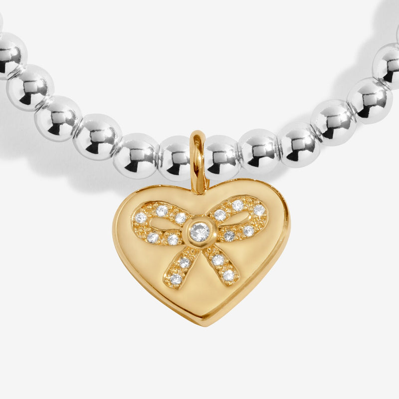 Close-up of Joma bestie bracelet gold heart charm with bow detail