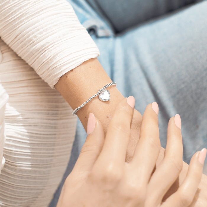 Joma A Little Happy Sweet 16th Birthday Bracelet worn on wrist, silver-plated beaded stretch Bracelet with a sparkly heart charm.