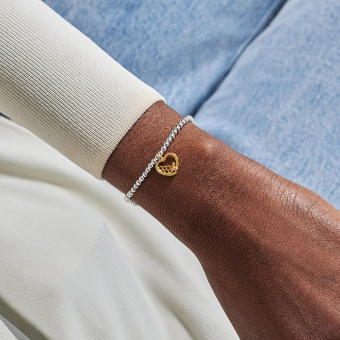 Silver beaded Bracelet worn on wrist with gold bee heart charm and honeycomb detail