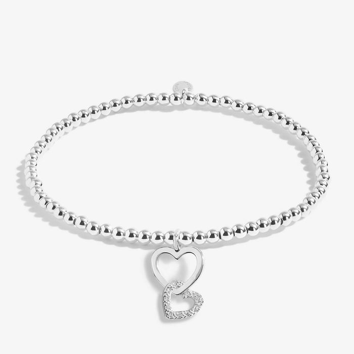 Joma A Little Mother and Daughter Bracelet laid flat, silver-plated beaded stretch Bracelet with heart charms.