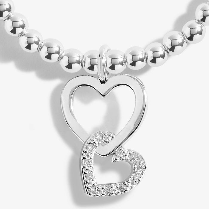 Close-up of Joma A Little Mother and Daughter Bracelet charm, silver interlinked hearts with crystal detail.