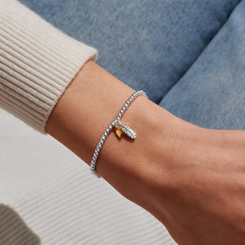 Silver beaded Bracelet worn on wrist with feather charm and gold heart charm for thinking of you gift
