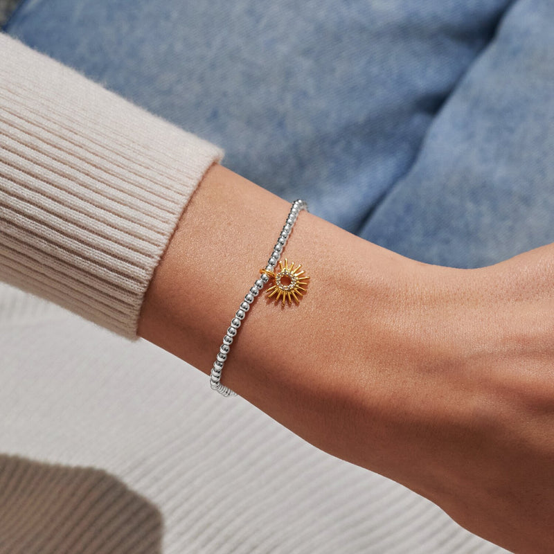 Silver beaded Bracelet worn on wrist with gold sunburst charm featuring crystal detail