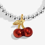 Close-up of red cherry charm on silver-plated beaded Bracelet with gold-tone stem detail