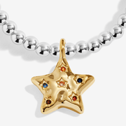 Close-up of gold-plated star bracelet charm with colourful stone accents