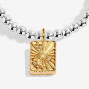 Close-up of gold-plated rectangular starburst charm with crystal details on beaded Bracelet
